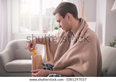 My delivery. Serious young man wearing a plaid while taking out the medicine from the bag Royalty-Free Stock Photo #1081297037