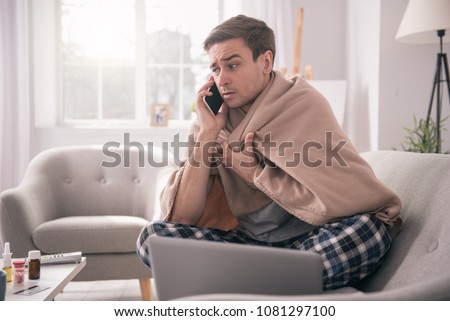 I am sick. Sad young man talking on the phone to his employer while asking about the sick leave Royalty-Free Stock Photo #1081297100