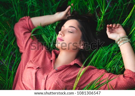 Young girl lying in grass with closed eyes day dreaming. Close up from above with copy-space. Sleep and dreaming concept.  Royalty-Free Stock Photo #1081306547