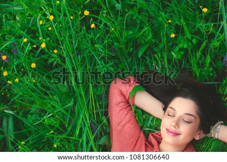 Smiling relaxed woman lying in grass with hands under the head with copy-space for text Royalty-Free Stock Photo #1081306640