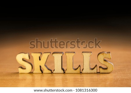 The word 'skills' made of wooden letters. wood inscription on table and dark black background