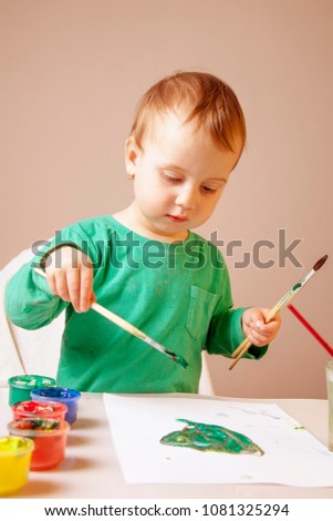 beautiful little child girl draws a picture paints (talent, creativity concept)