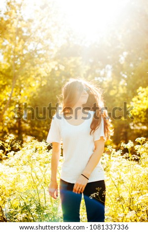 Cheerful young woman having fun at sunset in nature