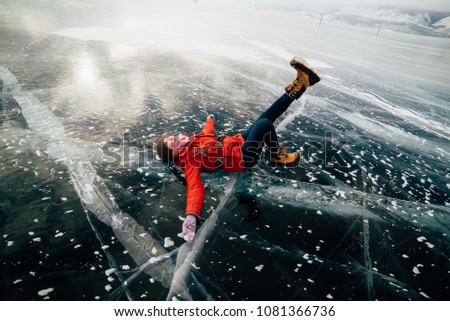the girl lies on the ice and enjoys the weather. she's having fun. she's happy. girl looks up at the sky