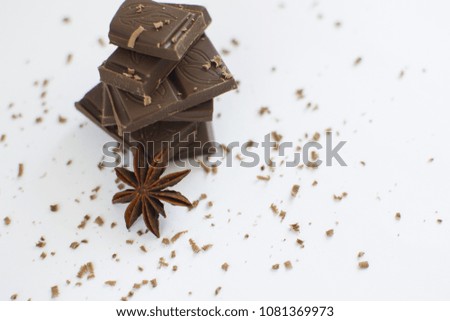 pyramid of chocolate pieces and star anise on white background in centre of picture, sprinkled with chocolate chips, horizontally