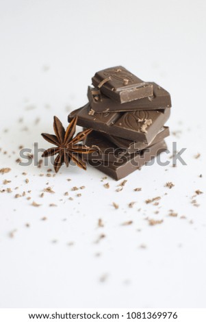 pyramid of chocolate pieces and star anise on white background in centre of picture, sprinkled with chocolate chips, vertically