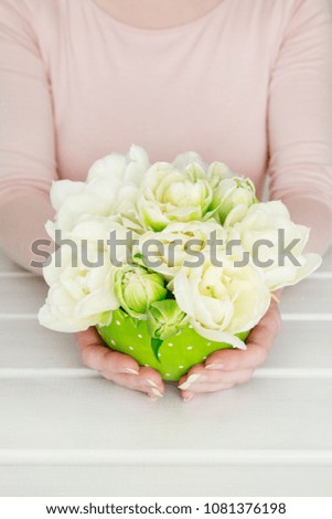 Woman holding eautiful spring floral arrangement with white tulips.