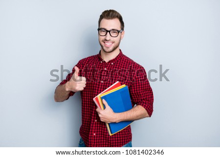 I recommend you to visit this course of English! Portrait of excited cheerful satisfied delightful handsome showing thumb-up and holding book, isolated on gray background Royalty-Free Stock Photo #1081402346