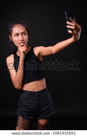 Studio shot of young beautiful Asian transgender woman against black background