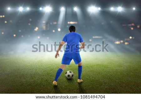 Back view of asian footballer with the ball on the field