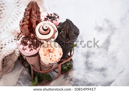Miscellaneous ice cream cone in a stand on a stylish light wooden background, the concept of ice cream and summer