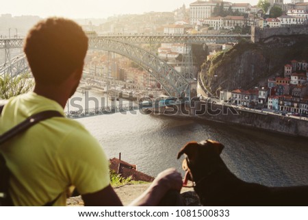 Traveler man with dog enjoying city view in Porto, famous iron bridge and Douro rive on background 