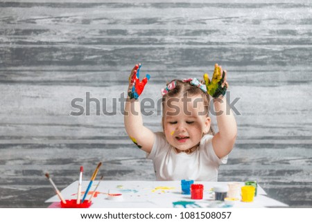 Little girl is drawing colors. Hands of girl is decorated of colors.