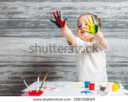 Little girl is drawing colors. Hands of girl is decorated of colors.