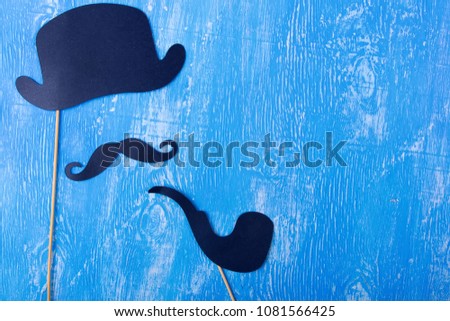 Hat, mustache and smoking pipe on a light blue wooden background. Place for text on the Father's Day holiday.