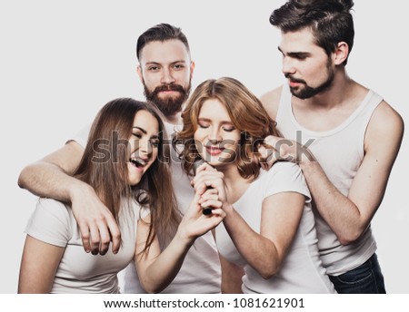 Group of friends playing karaoke over white background. Concept about friendship and people.