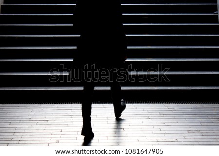 Urban night walk : Blurry silhouette of young elegant independent woman climbing up the city street public stairs in the peaceful moonlight , alone, from behind