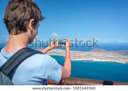 Young man taking pictures with his smartphone, in Lanzarote, Spain
