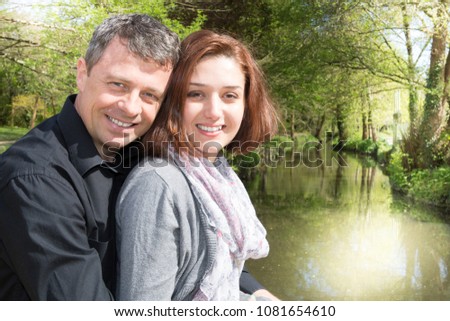 Portrait of a happy couple embracing while in the park near river lake