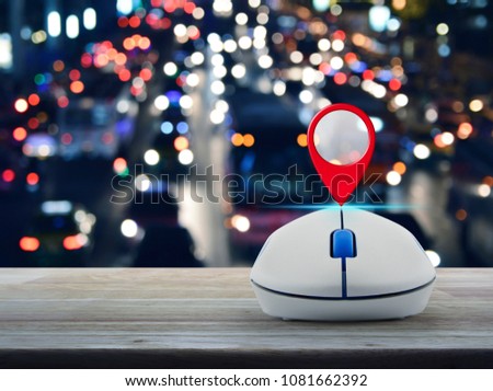 Map pin location button with wireless computer mouse on wooden table over blurred colourful night light city with cars, Map pointer navigation concept