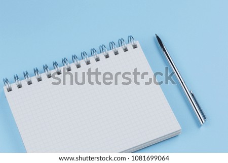 school notebook with pen on a blue table top view, office desktop, office supplies on a light blue background