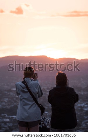 Two women taking a photo together at sunset over the mountain.