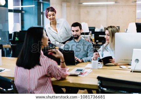 Successful male architect searching information on internet website on modern laptop computer with wireless connection teamworking with female colleagues on common project in stylish office