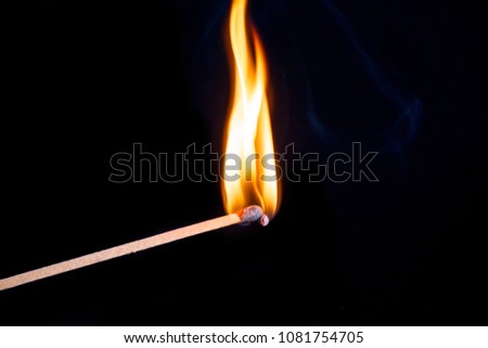 Burning match isolated on black background with smoke clouds. Macro photo.