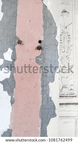 White antique wall with stucco and cracked gray and pink paint