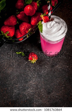 Cold strawberry  milkshake with fresh berries and mint on dark background copy space above