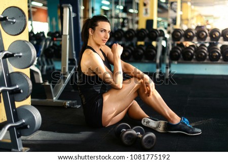 Relaxing after training. Beautiful young woman sitting at gym and having a brake after exercize. Young female at gym taking a break from workout. Sports fitness model. Healthy lifestyle concept
