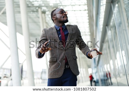 Happy African American business man dances while he listens to the music in his smartphone Royalty-Free Stock Photo #1081807502