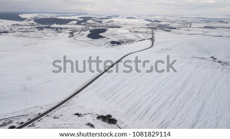 View from the air on the winter road in the field on which cars are going.