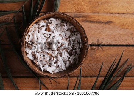 
fresh natural coconut shavings, palm leaves, half coconut on the background of wood. 