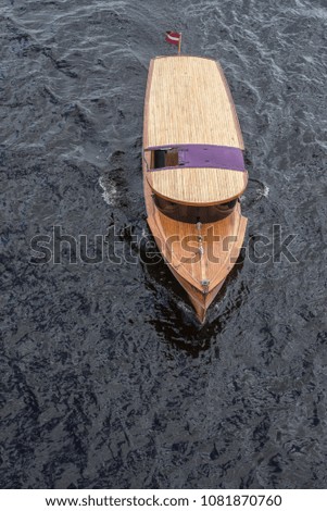A boat passing through a bridge with dark waters and boat made of wood
