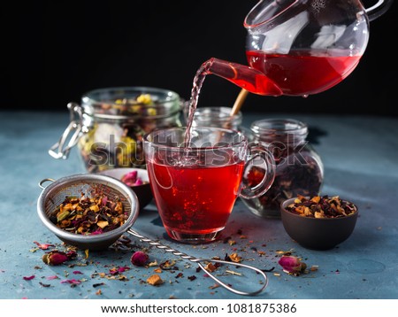 Process brewing tea,tea ceremony,Cup of freshly brewed fruit and herbal tea, dark mood.Hot water is poured from the kettle into a cup with tea leaves. Royalty-Free Stock Photo #1081875386