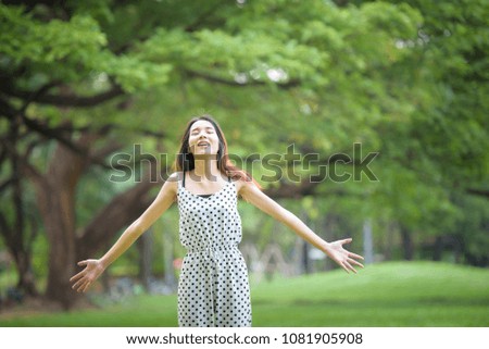 Relax time! Happy asian woman standing in the garden while her point arm to air