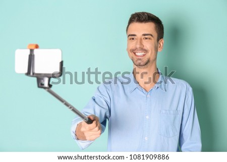 Young handsome man taking selfie against color background