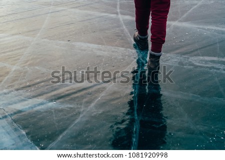 the girl went for a walk before dawn. walking on a frozen pond. winter vacation. the girl goes on the ice. boots do not slip