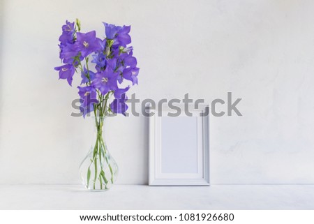 Mockup with a white frame and summer blue flowers in a vase on a light background