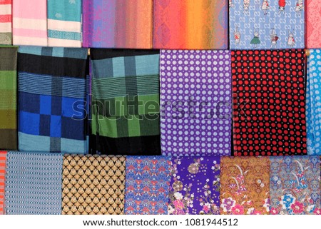 Fabrics made of cotton. View from foreground. Multicolored cotton fabrics are spread out on the table. Cotton fabrics for sewing clothes and bed linen. Sewing and tailoring. Satin and cotton.