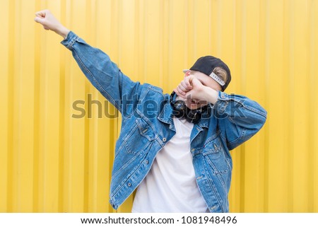 Young man throws dab on the background of a yellow wall. Royalty-Free Stock Photo #1081948496