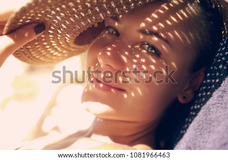 Pretty woman on the beach, closeup portrait of a nice female hides her face from the sun under a straw hat, skin protection, happy healthy summer vacation                                Royalty-Free Stock Photo #1081966463