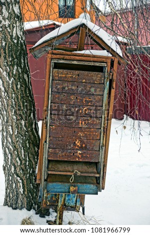 Old rusty soviet mailbox on the street in the snow near the birch