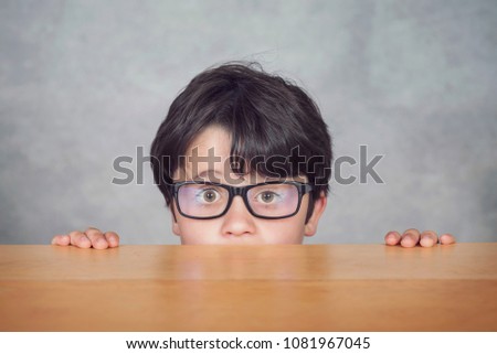boy with glasses on a wooden table
