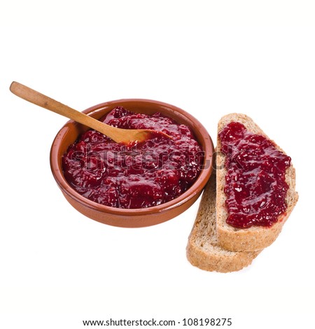 Raspberry jam in a clay bowl with a wooden spoon, and two slices of bread isolated on white background