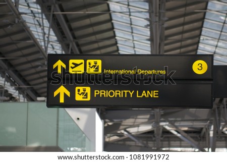 Departure and priority lane information board sign with yellow and white character on black background at international airport terminal.
