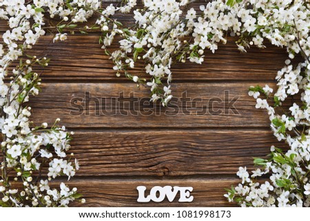 Close-up photo of Beautiful white Flowering Cherry Tree branches with  white letters love. Wedding, engagement or betrothal concept on vintage wooden background. Top view, greating card. 
