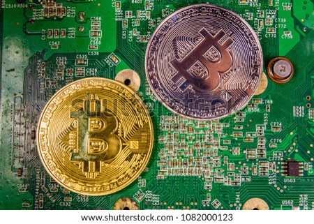 Golden and silver bitcoins on green circuit board