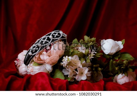 handmade hair accessory, hairband black and white beads lie with bouquet of flowers on a red fabric